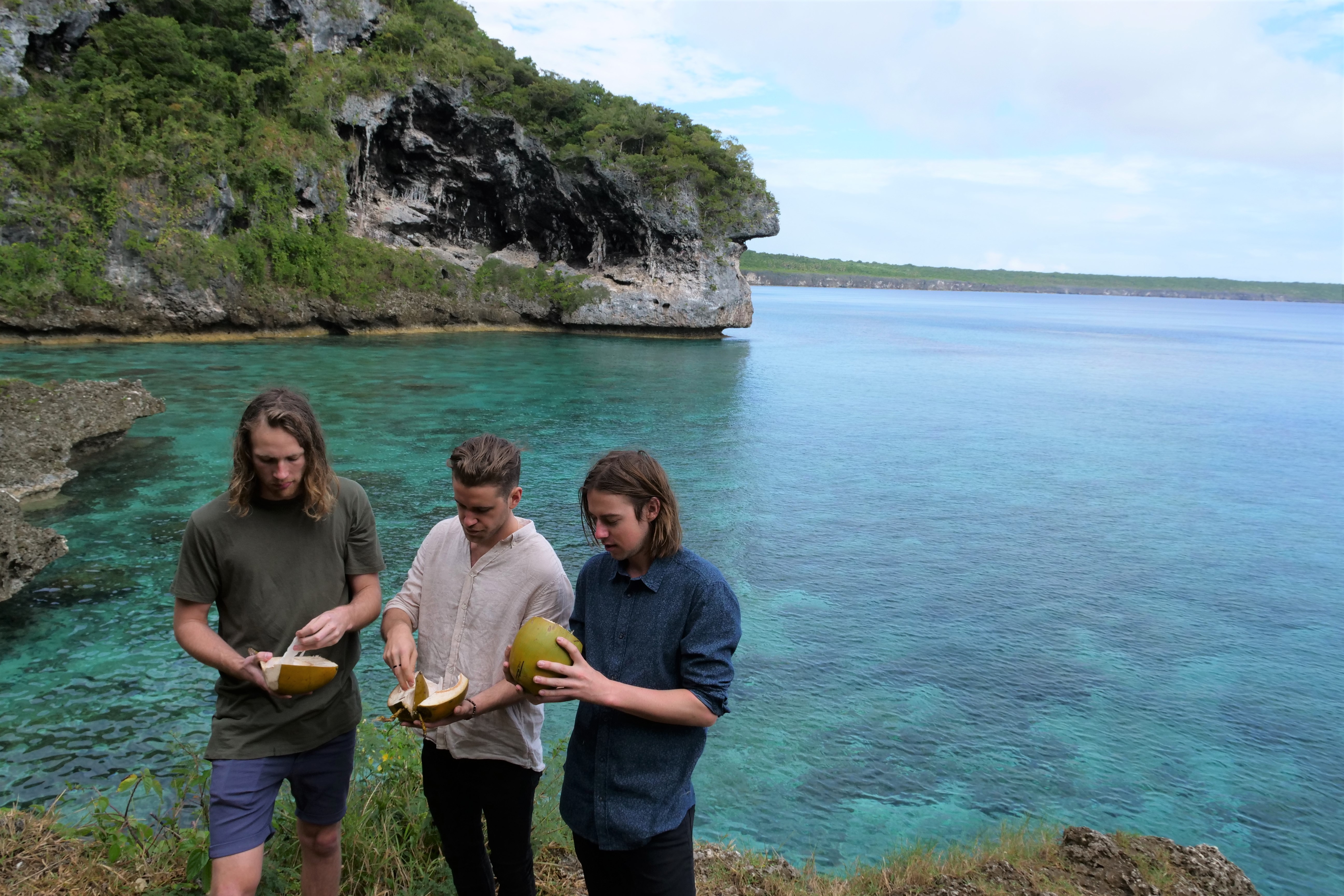 3 males eating coconuts